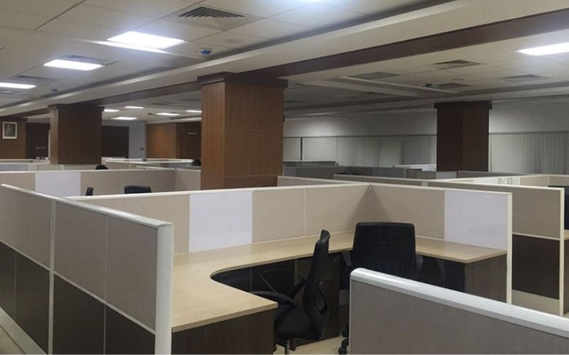 An office space featuring cubicles and desks, designed by commercial interior designers in Bangalore.