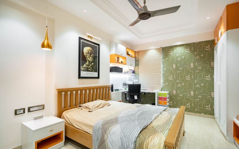 A cozy bedroom in Kolkata's home interior design, featuring a bed, chair, and table.