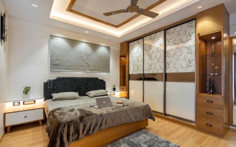 Bedroom with green walls and wooden floors in Kolkata home interior design.