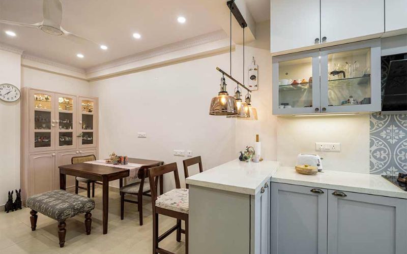 A modern kitchen featuring a dining table, microwave, and refrigerator, showcasing interior design trends in Bangalore.