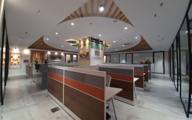 A large office environment with a distinctive circular ceiling and various tables, crafted by an interior designer in Bangalore.