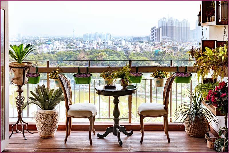 A charming English style balcony featuring potted plants and chairs, reflecting the artistry of Kolkata's interior design.