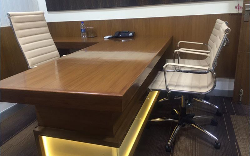 A modern office desk featuring two chairs and a phone, designed by an office interior designer in Kolkata.