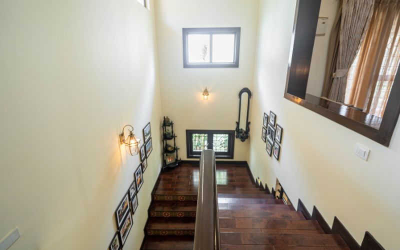 An elegant stairway in a home, featuring decorative pictures on the wall, ascending to the second floor.