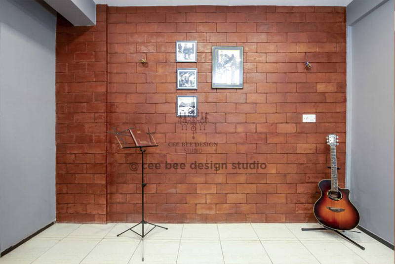 A 3bhk apartment's home interior design showcases a guitar and drum in front of a brick wall.