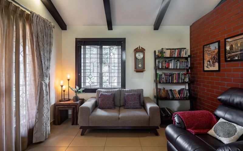 A cozy living room featuring a comfortable couch, a bookshelf filled with books, and a bright window illuminating the space.