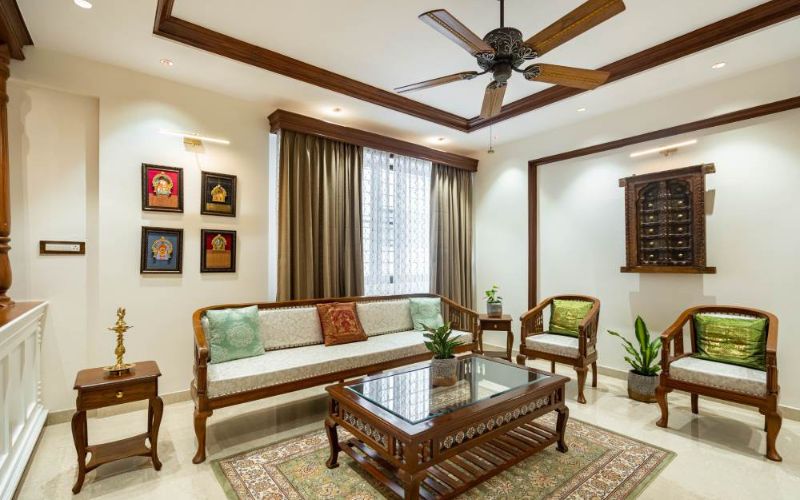 Elegant living room with wooden furniture and ceiling fan, designed by a Bangalore interior designing company.