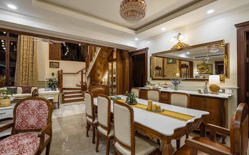 A stylish dining room featuring a large mirror and an elegant chandelier, designed by an interior designer in Kolkata.