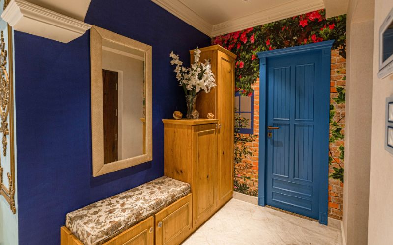 A stylish luxurious hallway adorned with blue walls and a wooden bench, exemplifying interior design aesthetics in Kolkata.