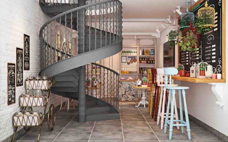 A spiral staircase elegantly winds through a cozy cafe interior in Bangalore, enhancing the room's charm and design.