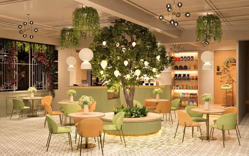 A cafe interior in Bangalore featuring green chairs and a decorative tree, creating a vibrant and inviting atmosphere.