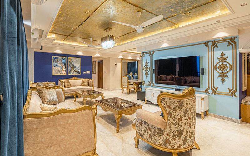 An inviting living room with vibrant blue walls and sophisticated gold accents, designed by a Kolkata interior designer.