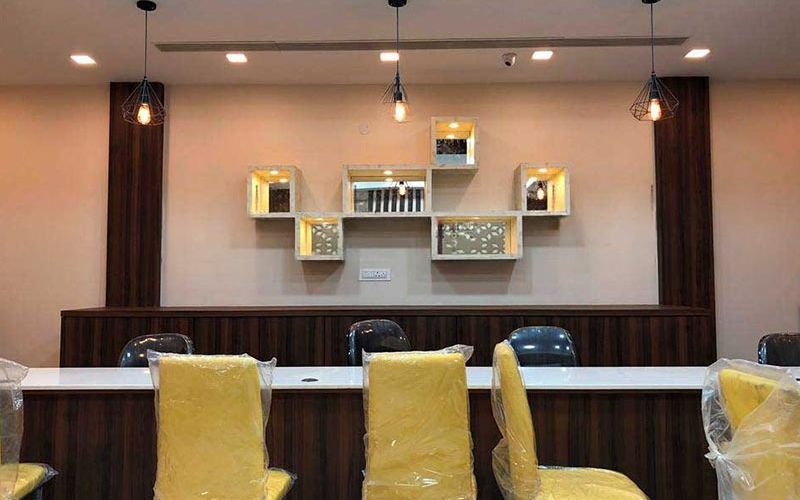 Elegant jewellery store in Kolkata showcasing a long table with yellow chairs and a decorative shelf for merchandise.