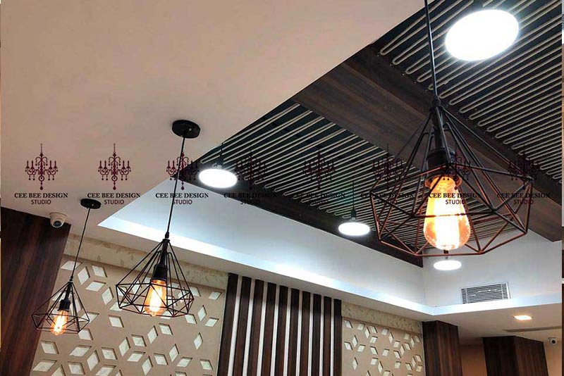 A trio of stylish light fixtures hanging from the ceiling, contributing to the jewellery showroom's inviting atmosphere, designed in Kolkata.