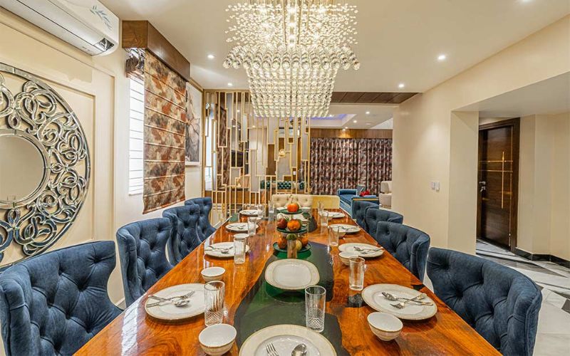 Elegant dining room showcasing blue chairs and a chandelier reflecting the expertise of an interior designer in Kolkata.