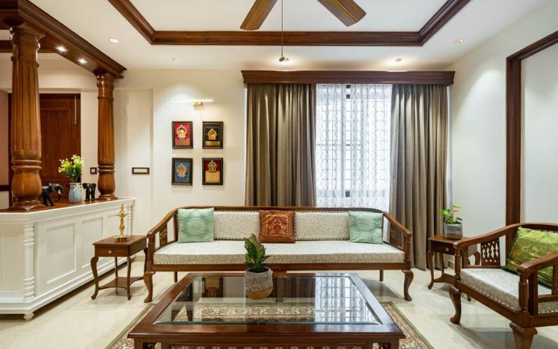 A cozy traditional living room featuring elegant wooden furniture and a stylish ceiling fan, designed by top interior designers in Kolkata.