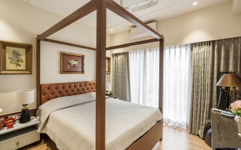 A stylish bedroom featuring a four-poster bed and a large mirror, designed by an interior designer in Kolkata.