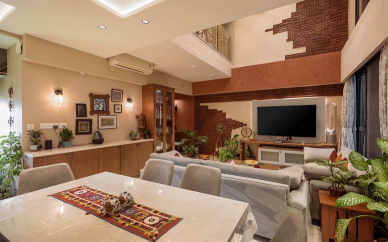 A stylish living room featuring a large TV and a dining table, showcasing the expertise of interior decorators in Kolkata.