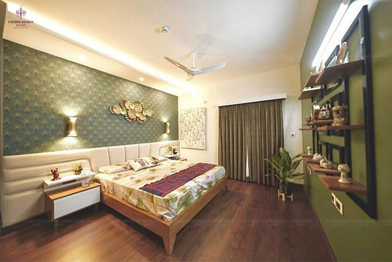 A cozy bedroom in Kolkata with a bed, chair, and ceiling fan in the home interior design.