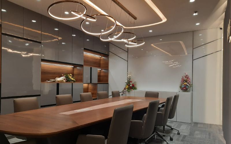 A conference room featuring a wooden table surrounded by chairs, designed by interior decorators in Kolkata.