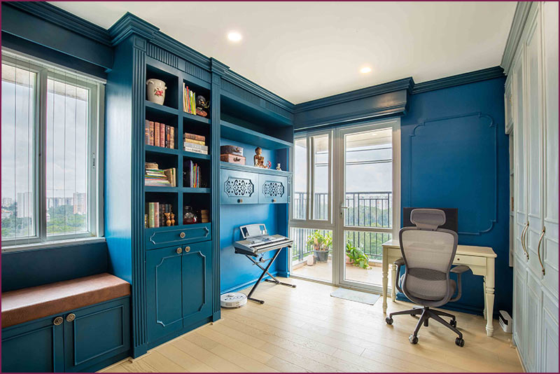 A home office with blue walls and a desk, showcasing modern home interior design.