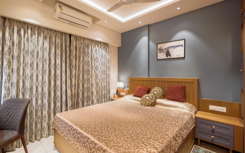 Cozy bedroom interior displaying a bed, chair, and ceiling fan, highlighting the expertise of Bangalore's interior designers.