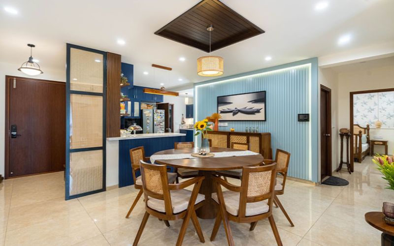 A stylish dining room featuring a blue wall and a wooden table, designed by an interior designer in Bangalore.