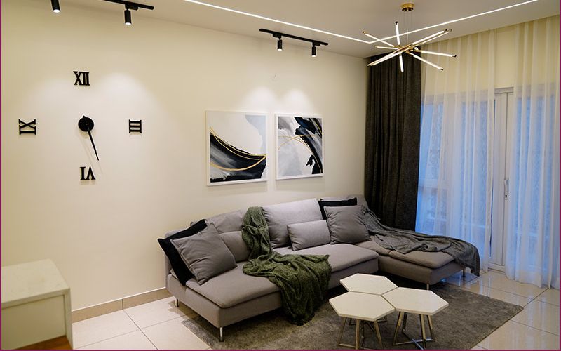 A contemporary living room featuring a stylish couch, elegant coffee table, and a wall clock, designed by an interior designer in Bangalore.