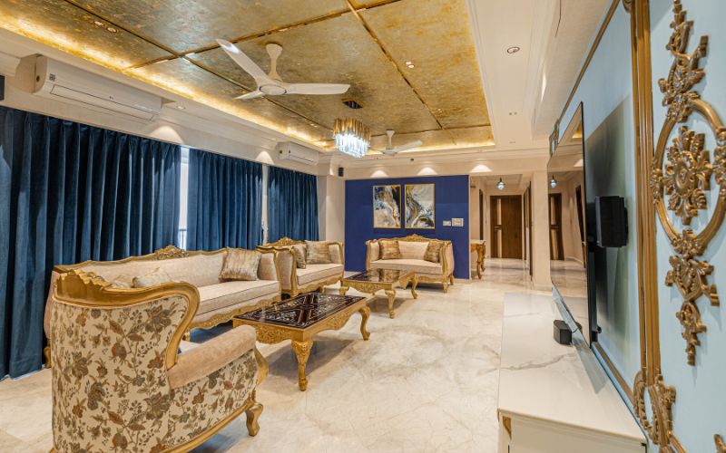 An inviting living room with luxurious gold and blue decor, exemplifying the creativity of interior designers in Bangalore.