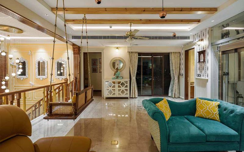 A spacious living room featuring a large wooden ceiling and an elegant chandelier, designed by an interior designer in Kolkata.