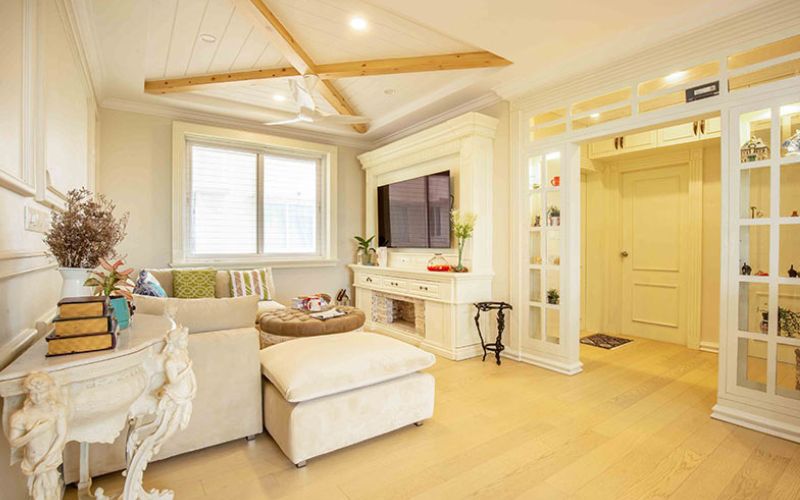 A stylish living room featuring white walls and wooden floors, designed by an interior designer in Kolkata.