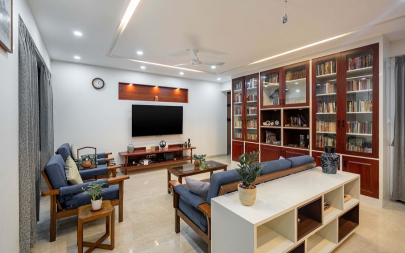 A cozy living room featuring a television and bookshelves, showcasing modern interior design elements from Kolkata firms.