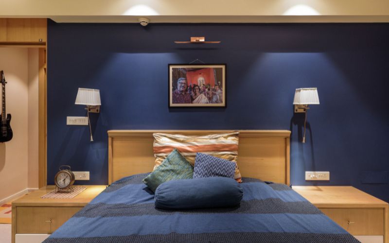 A contemporary bedroom with blue walls and a guitar displayed on the wall, reflecting Bangalore's interior design trends.