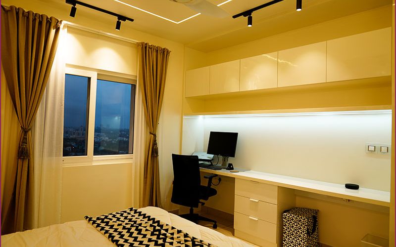 A stylish bedroom featuring a desk and a window, designed by an interior designer in Bangalore.