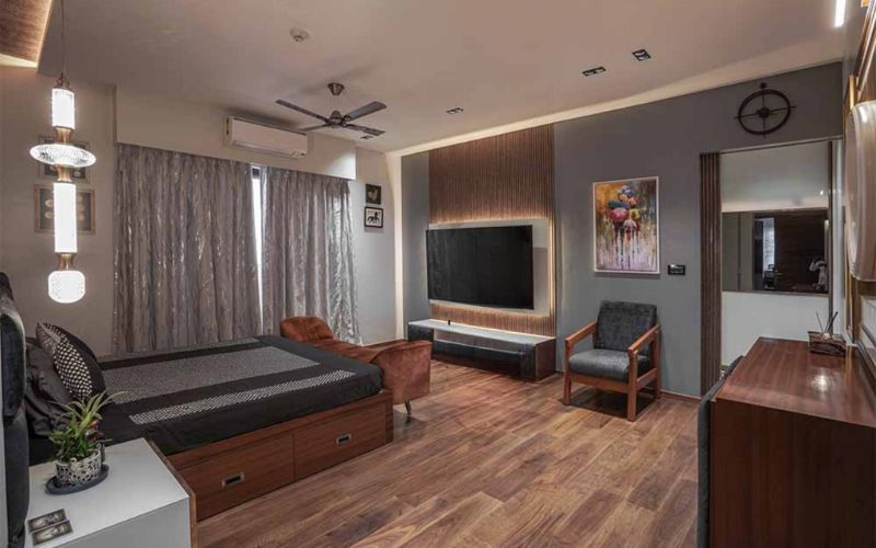 Modern bedroom with wooden flooring and a flat-screen TV, showcasing the work of Bangalore's interior designers.