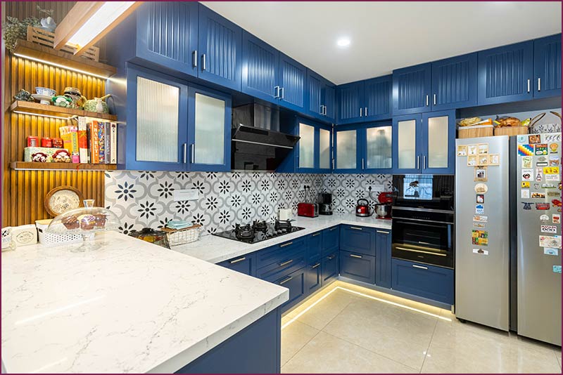 A modern kitchen featuring blue cabinets and white countertops, designed by an interior design company in Bangalore.