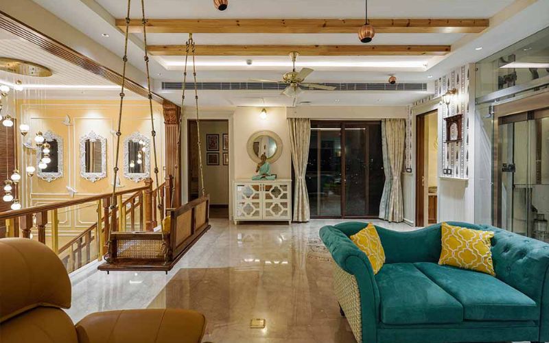 A luxurious living room featuring a large wooden ceiling and a stylish yellow couch, designed by top interior designers in Bangalore.