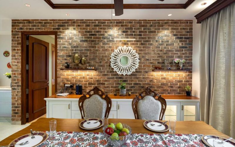 Elegant dining room showcasing a brick wall and a ceiling fan, reflecting the expertise of luxury interior designers in Bangalore.