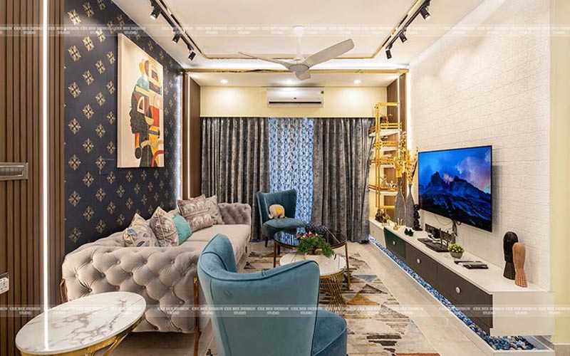 A modern living room with two blue chairs and a sleek flat screen TV mounted on the wall.