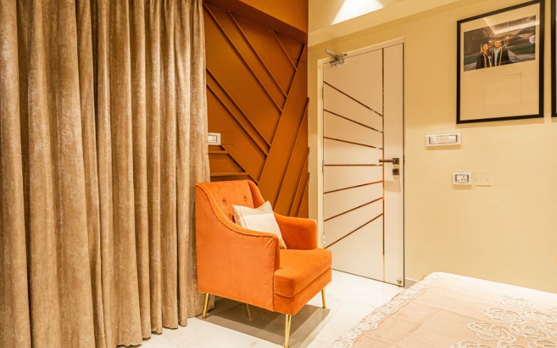 A luxury bedroom design with an orange chair and a cozy bed, reflecting the aesthetic of Kolkata's interior design firm.