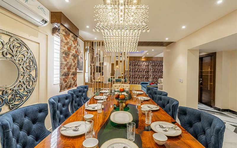 An elegant dining room adorned with blue chairs and a chandelier, reflecting the interior design trends in Bangalore.