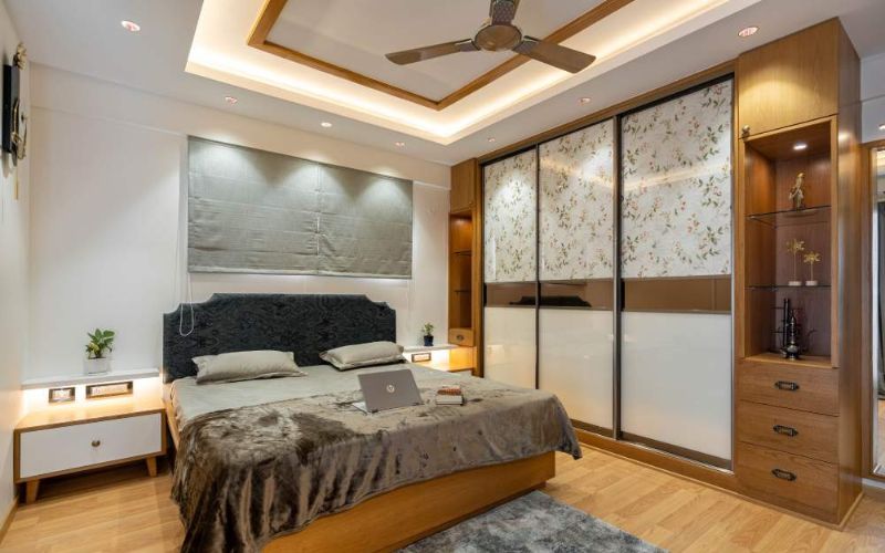 Bedroom with bed, dresser, and ceiling fan. Designed by a professional interior designer in Bangalore.