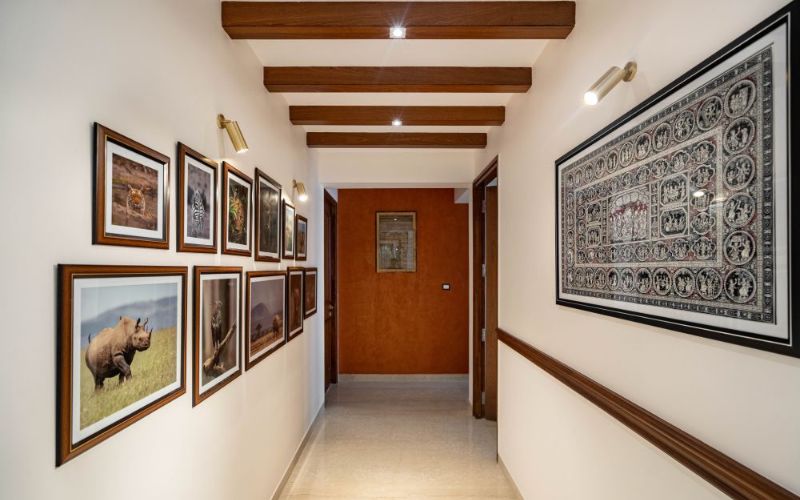 A hallway with framed pictures and a wooden ceiling, designed by an interior designer in Kolkata.