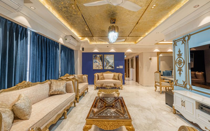 A classy luxurious living room featuring elegant gold and blue decor, showcasing modern interior design trends in Kolkata.